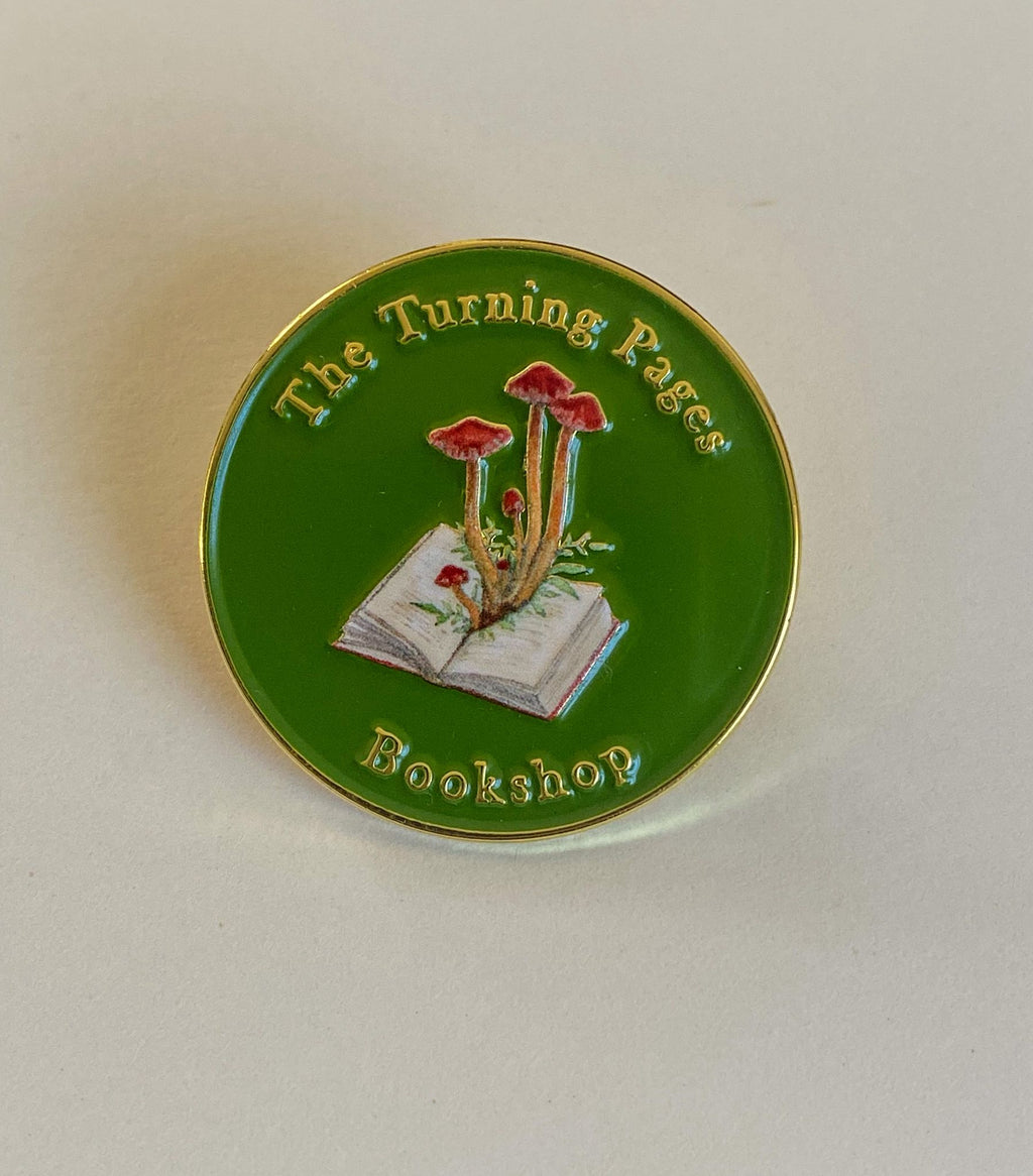 The Turning Pages Enamel pin sits on a white background