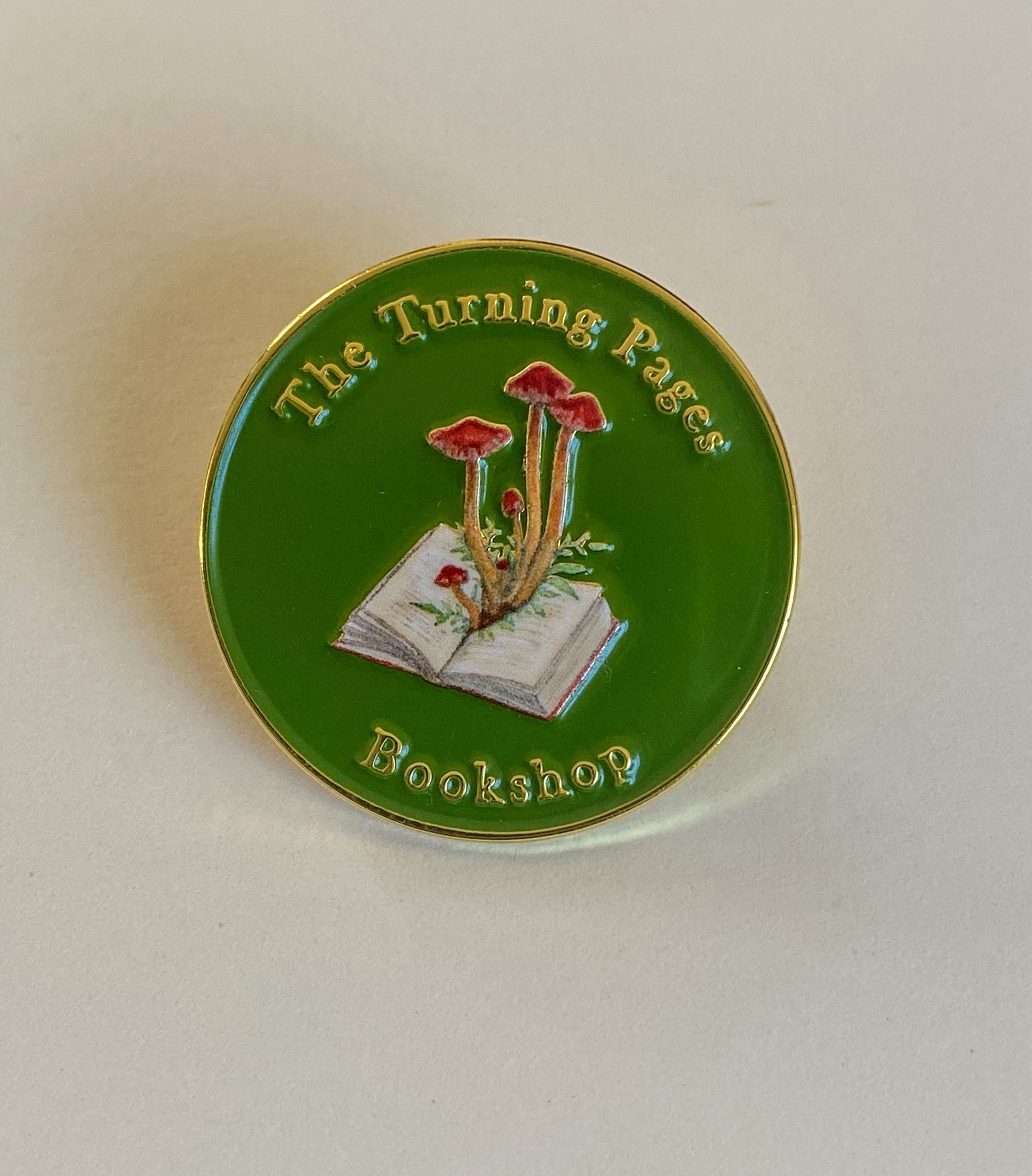 The Turning Pages Enamel pin sits on a white background
